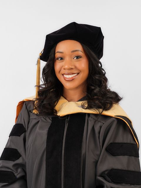 Dr. Jessica Gaddy smiles at the camera, wearing full academic regalia.