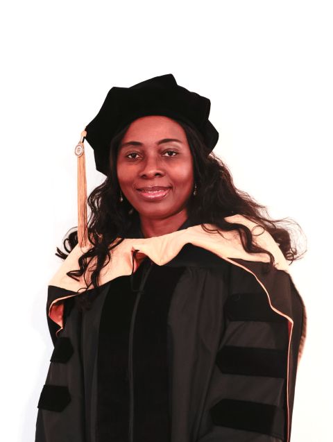 Dr. Rosemary Mbongo smiles at the camera, wearing full academic regalia.