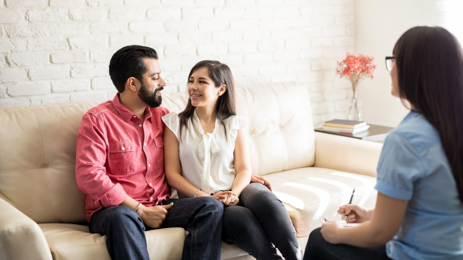 Smiling couple on a couch sitting across from a therapist