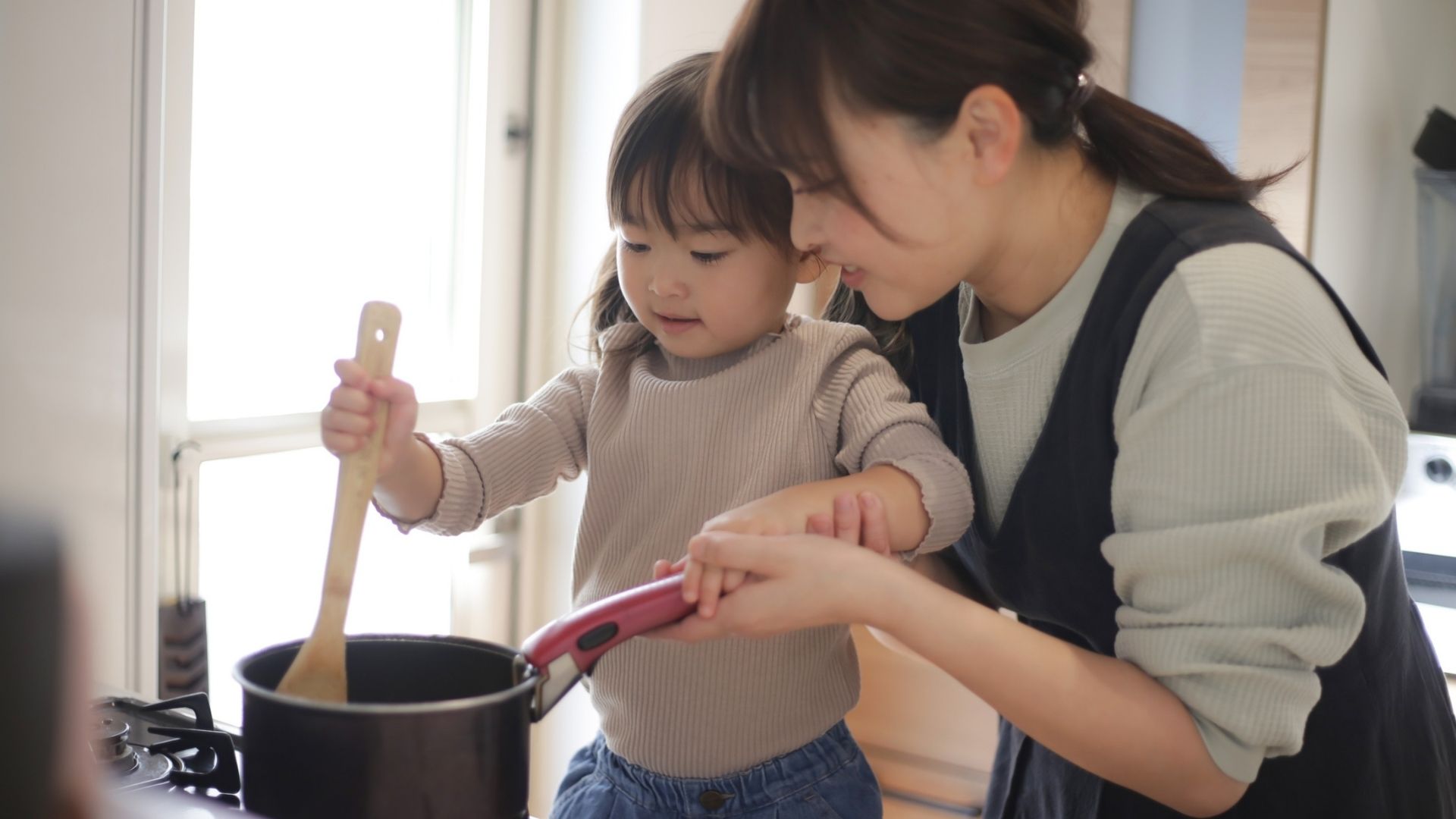 Happy mother and child cooking together on a stovetop