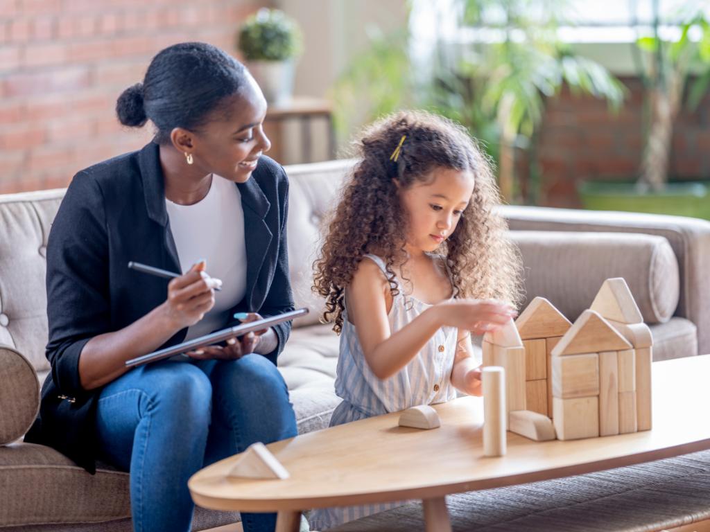 A therapist working with a young girl who is building with blocks