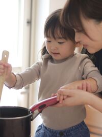 Happy mother and child cooking together on a stovetop