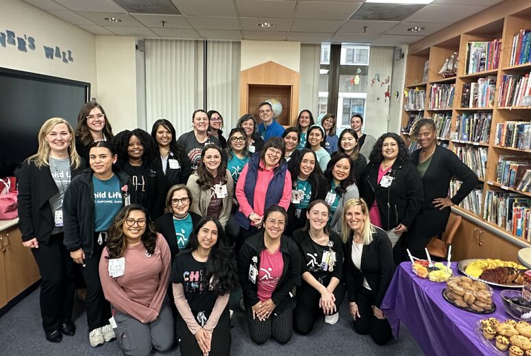 Child Life leaders, faculty, and students posed together as a group indoors beside bookshelves
