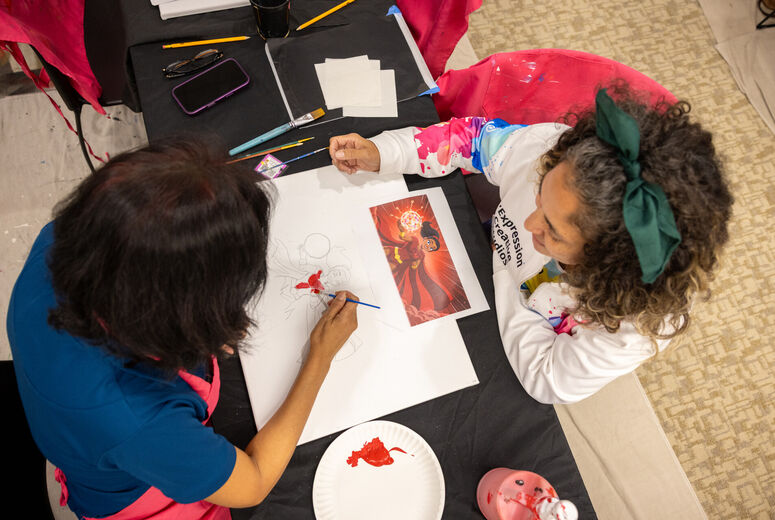 Two people draw on same piece of paper