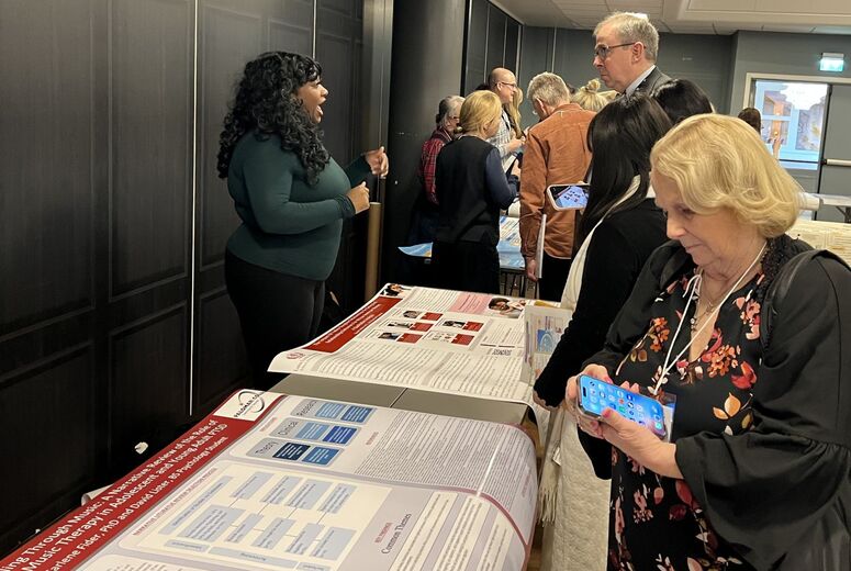 School of Behavioral Health student Neeah Lofton engages with attendees reviewing the 'Healing Through Music' research poster during the 2026 IFTA World Congress poster session in Bergen, Norway.