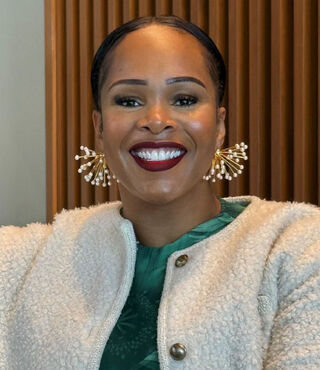 Dr. Imani Austin smiles at the camera, wearing a green shirt under a cream jacket.