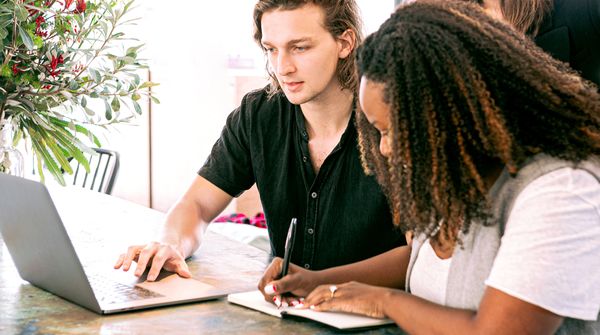 Three individuals looking at a laptop for work