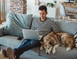 man using laptop beside dog