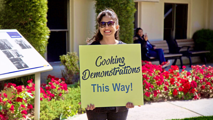 student holding wayfinding cooking sign