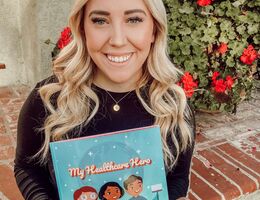 Alumna Sam Ochse, MS, CCLS holds a copy of her recent book, My Healthcare Hero