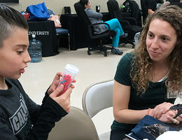 A Child Life Specialist graduate student engages with a young boy.