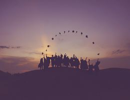 Group of graduates throwing hats at dawn