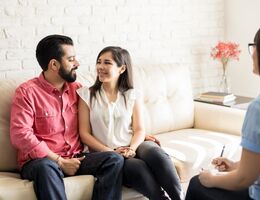 Smiling couple on a couch sitting across from a therapist