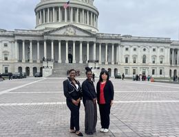 Two students and one faculty member in front of the U.S. Capitol