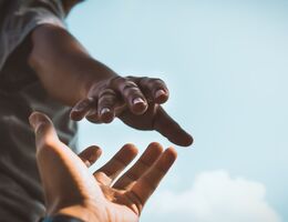 Hand reaching out to grab another hand in aid
