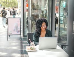 Woman works on laptop outside a café
