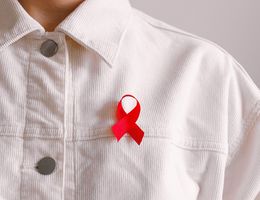 Person wearing a red World AIDS Day ribbon on their white button-up shirt