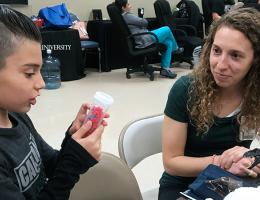 A Child Life Specialist graduate student engages with a young boy.