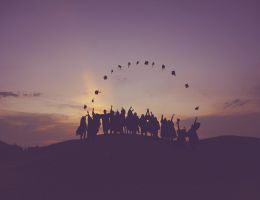 Group of graduates throwing hats at dawn