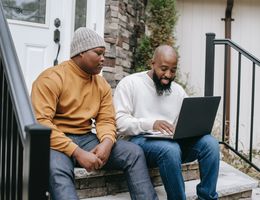 Two individuals work together on a laptop
