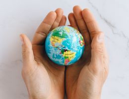 person holds model of the world in their hands